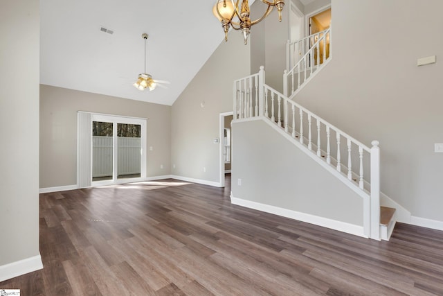 unfurnished living room with baseboards, dark wood finished floors, a high ceiling, stairs, and ceiling fan with notable chandelier