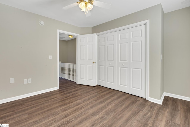 unfurnished bedroom featuring dark wood-style floors, ceiling fan, a closet, and baseboards