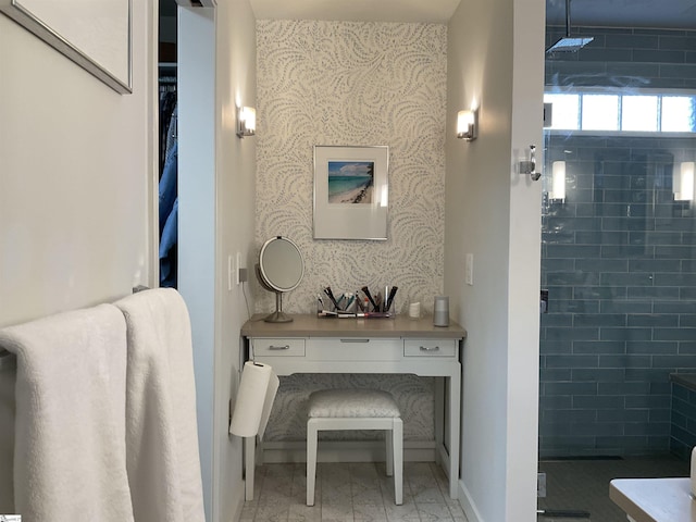 bathroom featuring wallpapered walls, a shower stall, an accent wall, and baseboards