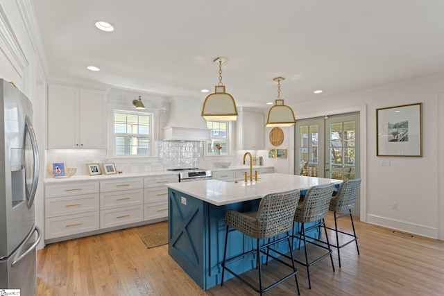 kitchen featuring appliances with stainless steel finishes, light countertops, white cabinetry, and decorative light fixtures