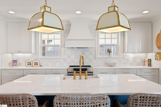 kitchen with a breakfast bar, white cabinetry, and custom range hood