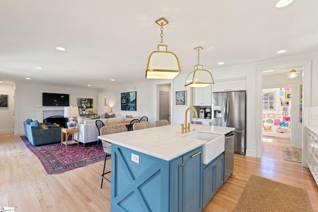 kitchen featuring white cabinets, light countertops, blue cabinetry, appliances with stainless steel finishes, and pendant lighting