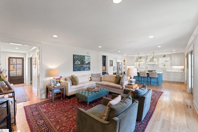 living area featuring light wood-style floors, recessed lighting, crown molding, and baseboards