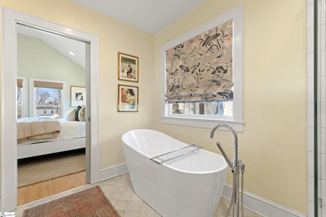 ensuite bathroom with a soaking tub, baseboards, a wealth of natural light, and connected bathroom