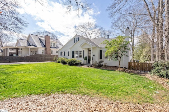 view of front facade featuring fence, a chimney, and a front lawn