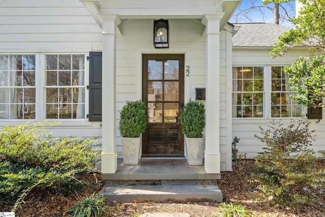 entrance to property featuring roof with shingles