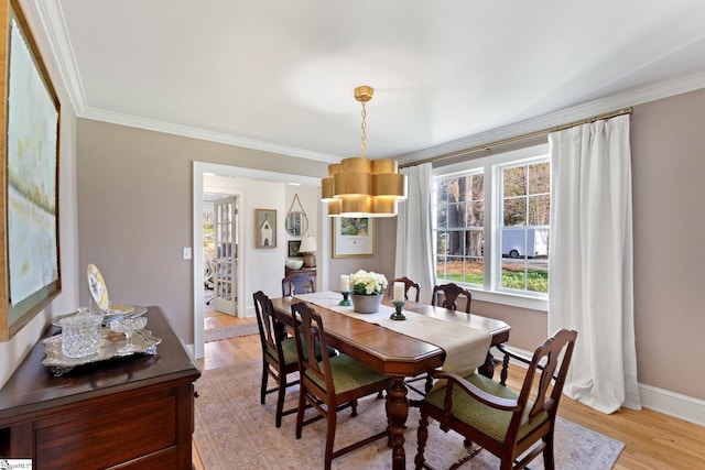 dining room featuring light wood-type flooring, baseboards, and crown molding