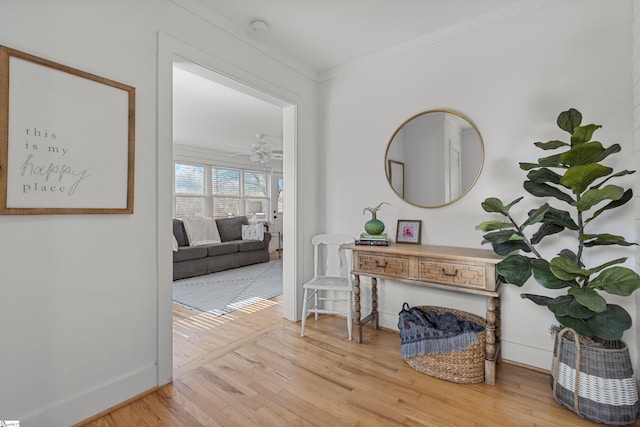 hallway with baseboards, light wood-type flooring, and crown molding