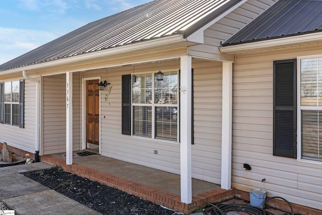 view of exterior entry with covered porch and metal roof