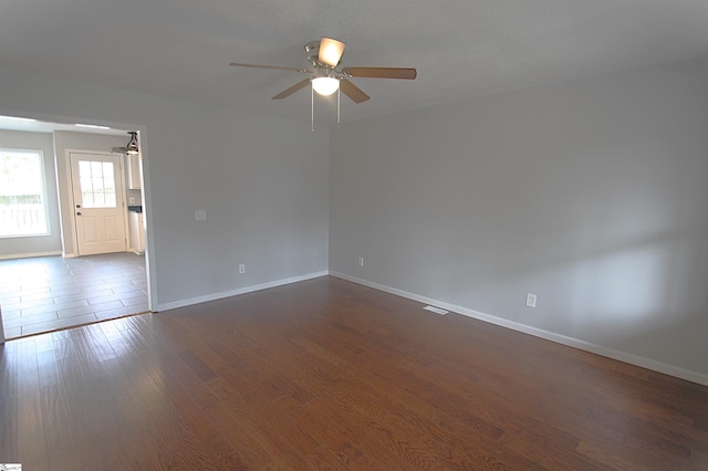 spare room featuring dark wood-type flooring, baseboards, and a ceiling fan