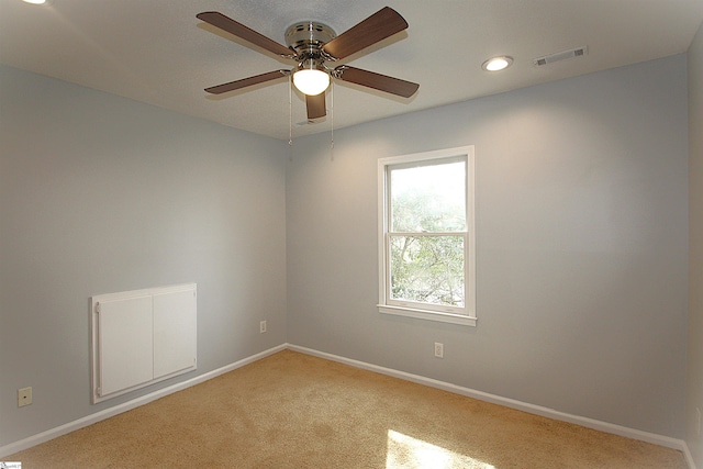 spare room featuring light carpet, ceiling fan, visible vents, and baseboards