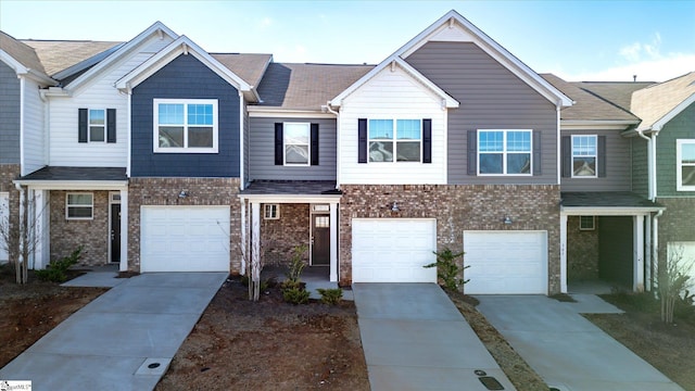 townhome / multi-family property with driveway, brick siding, and an attached garage