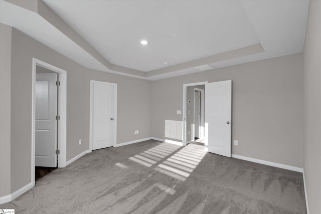 unfurnished bedroom with carpet floors, a tray ceiling, recessed lighting, and baseboards