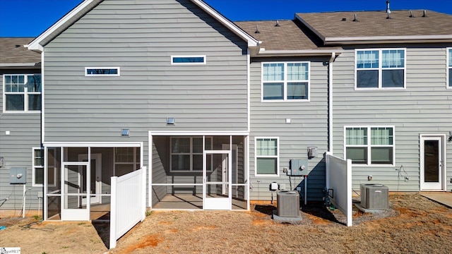 rear view of house with a sunroom, a shingled roof, and cooling unit