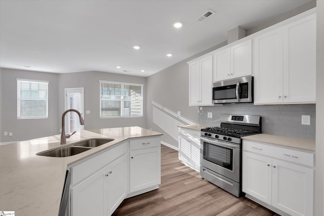 kitchen featuring light wood-style flooring, stainless steel appliances, a sink, visible vents, and white cabinets