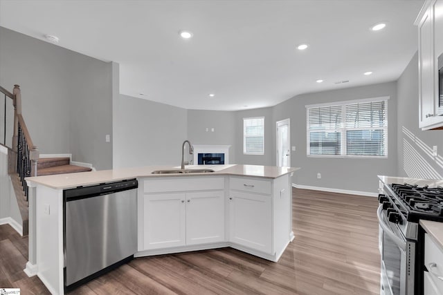 kitchen with appliances with stainless steel finishes, light countertops, white cabinets, and a sink