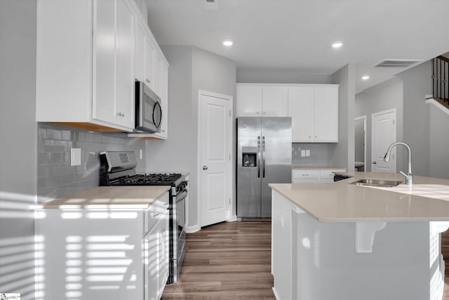 kitchen featuring a kitchen island with sink, stainless steel appliances, a sink, and white cabinetry