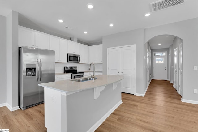 kitchen with a center island with sink, visible vents, white cabinets, appliances with stainless steel finishes, and a sink