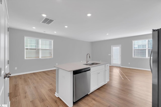 kitchen featuring a sink, visible vents, white cabinets, appliances with stainless steel finishes, and an island with sink