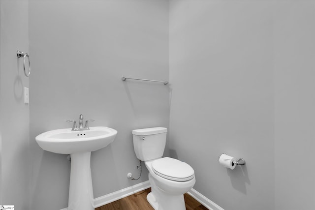 bathroom featuring a sink, wood finished floors, toilet, and baseboards