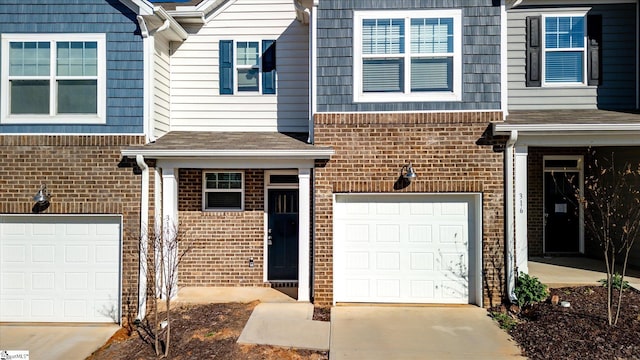 doorway to property with concrete driveway, brick siding, and an attached garage