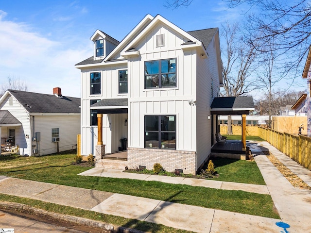 modern inspired farmhouse with brick siding, a shingled roof, board and batten siding, a front yard, and fence