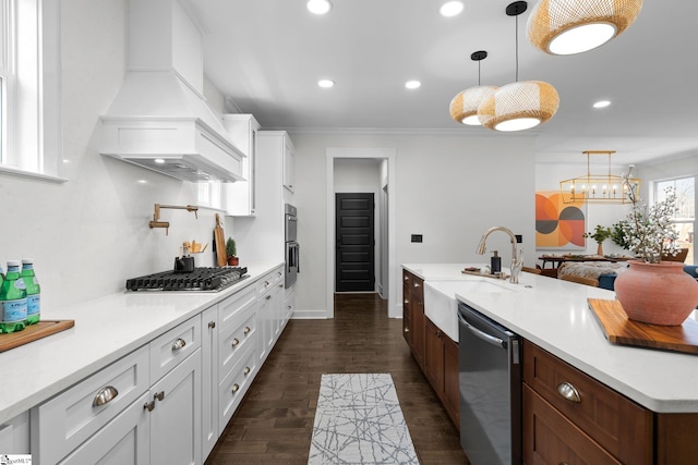 kitchen featuring stainless steel appliances, premium range hood, white cabinets, light countertops, and pendant lighting