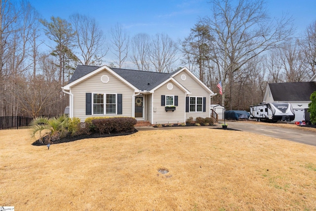 ranch-style house featuring driveway, a front lawn, a shingled roof, and fence