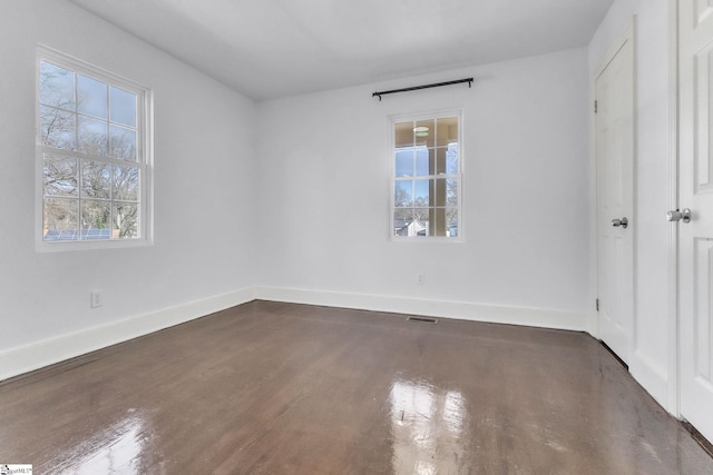 unfurnished bedroom with visible vents, multiple windows, baseboards, and dark wood-type flooring