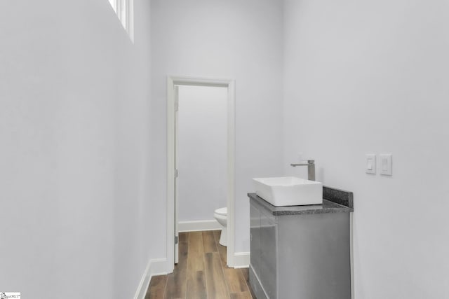 bathroom featuring baseboards, vanity, toilet, and wood finished floors