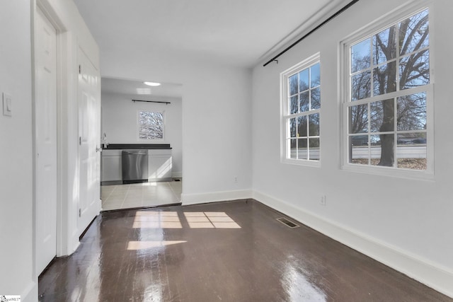 unfurnished room with dark wood-style flooring, visible vents, and baseboards