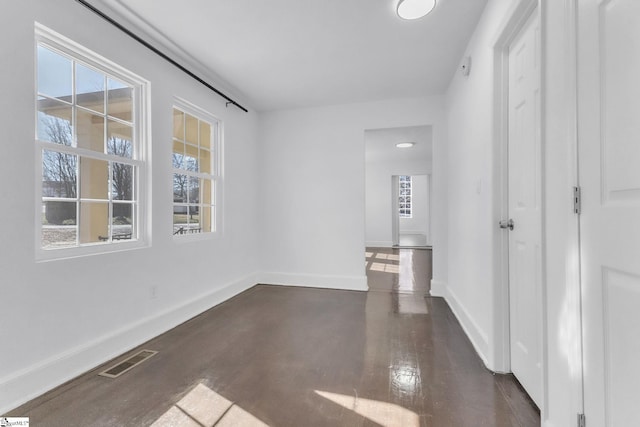 empty room with dark wood-style floors, baseboards, and visible vents