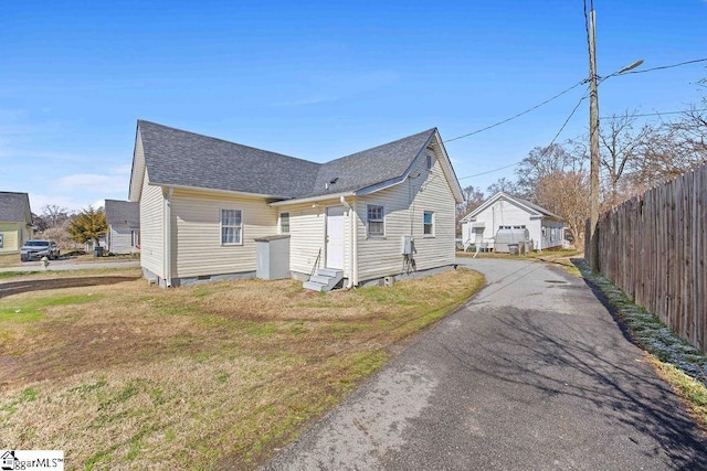 view of front of property featuring a shingled roof, fence, driveway, crawl space, and a front lawn