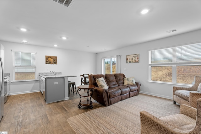 living area with baseboards, visible vents, wood finished floors, and recessed lighting