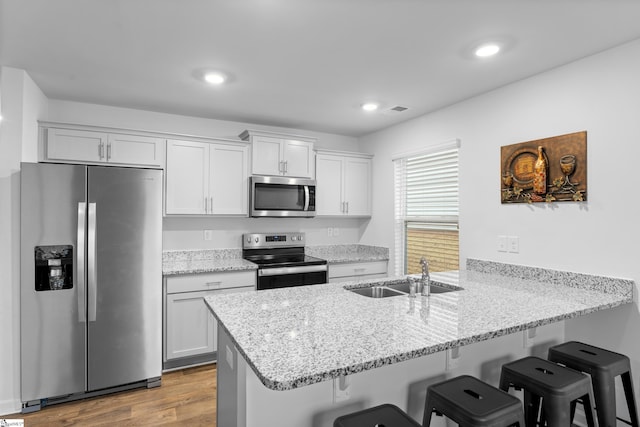 kitchen featuring a peninsula, appliances with stainless steel finishes, a breakfast bar, and white cabinetry