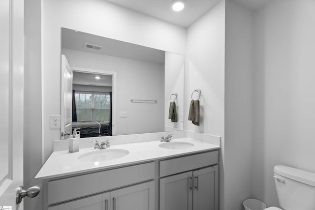 ensuite bathroom featuring toilet, visible vents, a sink, and ensuite bath