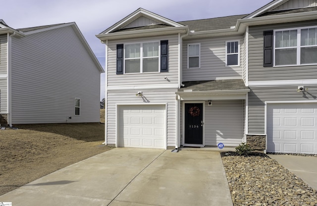 view of front facade featuring concrete driveway, board and batten siding, an attached garage, and roof with shingles
