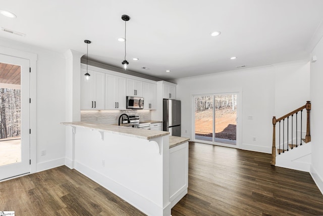 kitchen featuring decorative light fixtures, stainless steel appliances, visible vents, white cabinetry, and a peninsula