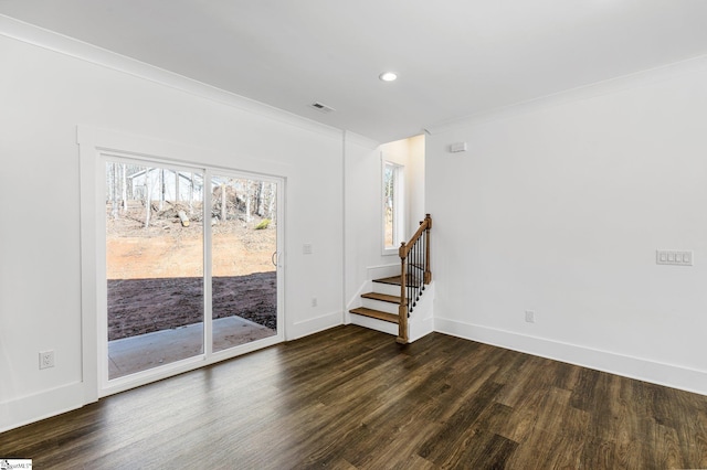 empty room with dark wood-type flooring, visible vents, baseboards, stairs, and ornamental molding