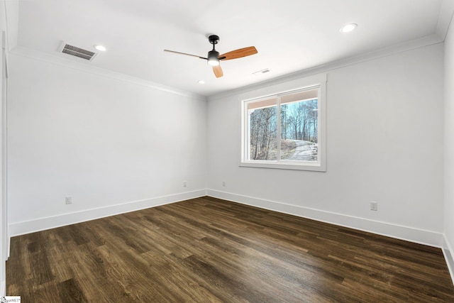 empty room with baseboards, visible vents, dark wood-type flooring, and ornamental molding