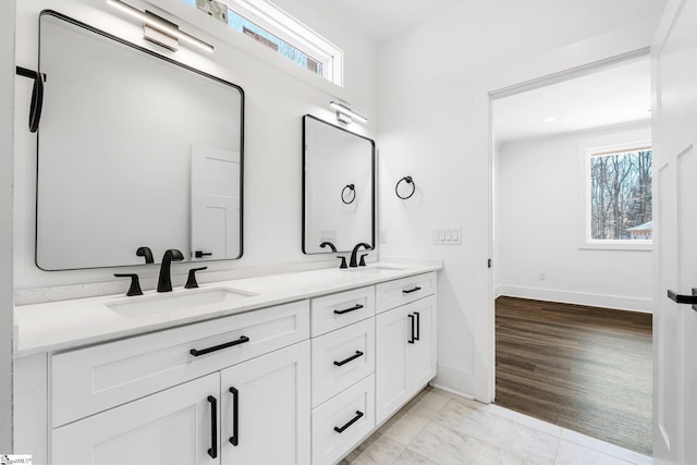 full bath with double vanity, a sink, and a healthy amount of sunlight