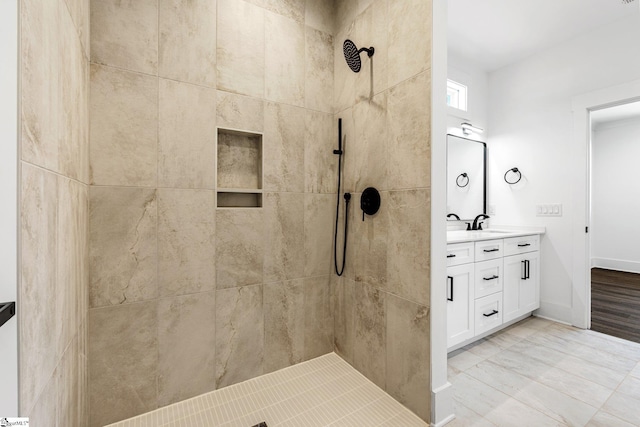 bathroom featuring a tile shower, vanity, and baseboards