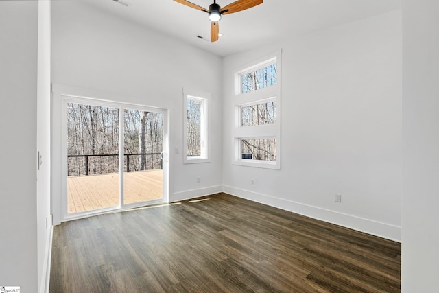 spare room featuring a high ceiling, dark wood-style flooring, visible vents, a ceiling fan, and baseboards