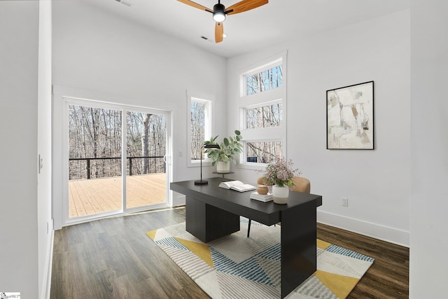 office area with a ceiling fan, a high ceiling, dark wood finished floors, and baseboards