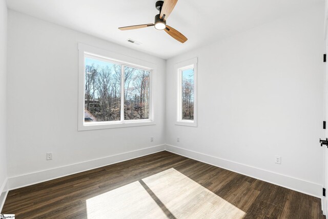 unfurnished room featuring a ceiling fan, baseboards, visible vents, and dark wood-style flooring