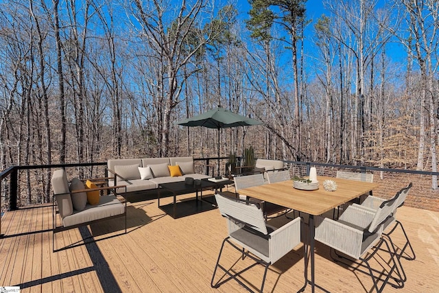 wooden terrace featuring outdoor dining area, outdoor lounge area, and a view of trees