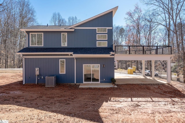 back of property with a carport, a shingled roof, a patio, and cooling unit