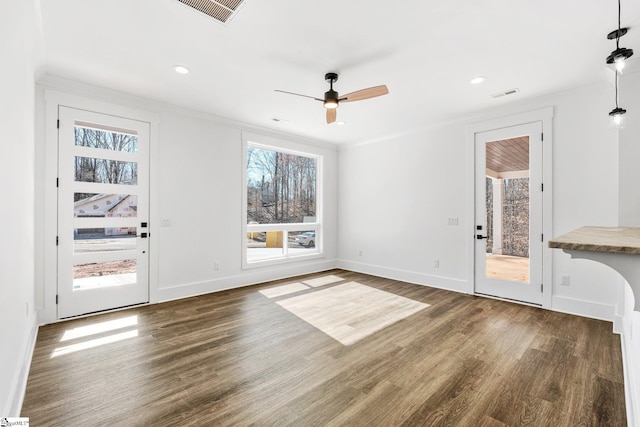 unfurnished living room featuring ornamental molding, dark wood finished floors, visible vents, and baseboards