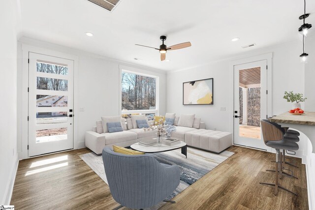 living room featuring light wood-style floors, recessed lighting, visible vents, and crown molding