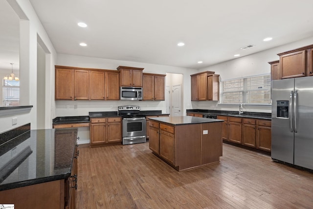 kitchen with stainless steel appliances, a center island, brown cabinets, and dark wood finished floors